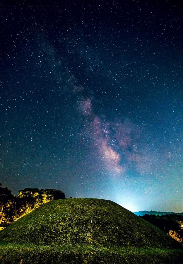 高松塚古墳の墳丘と幻想的な星空を写した写真