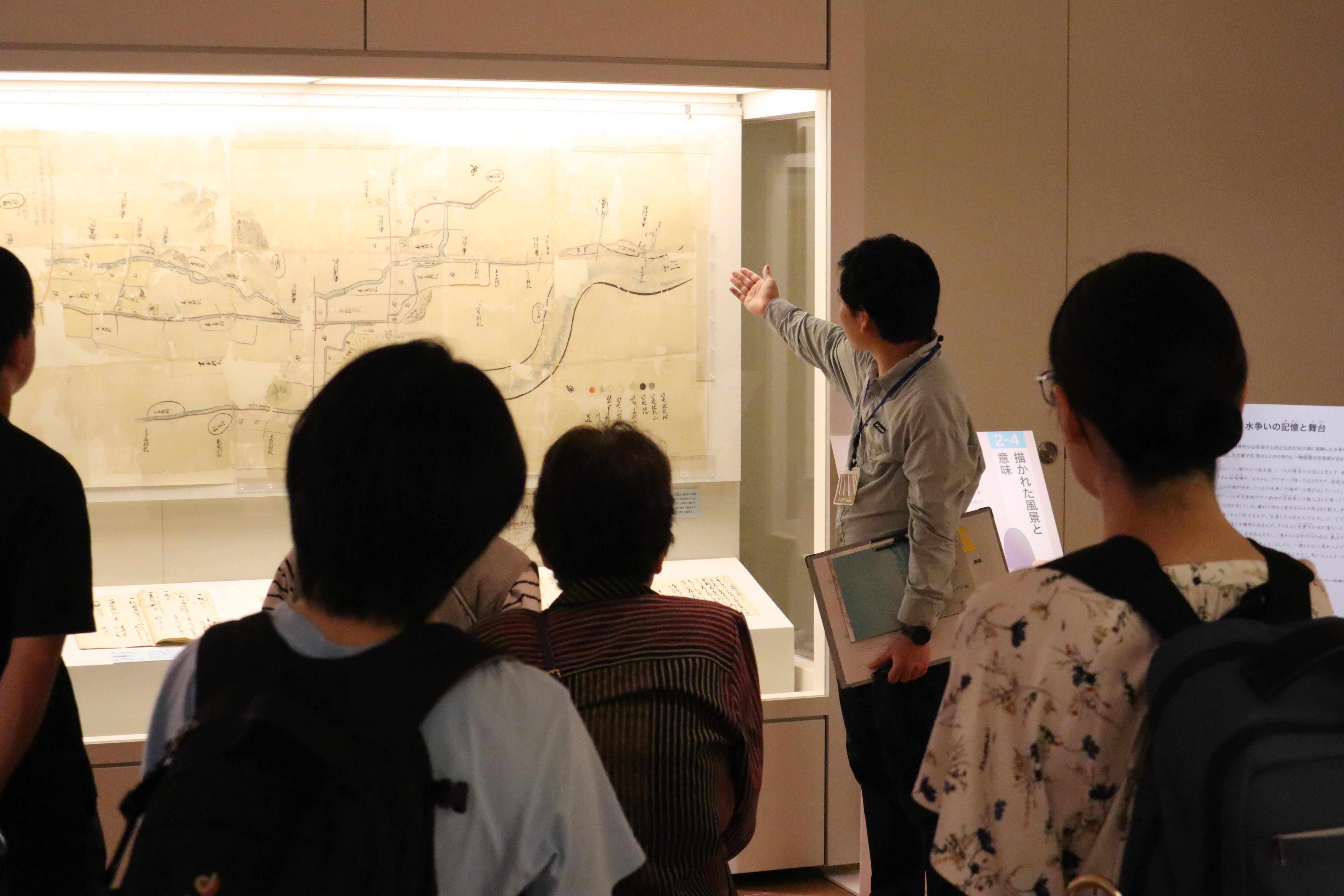 研究員が展示物の前で解説する画像