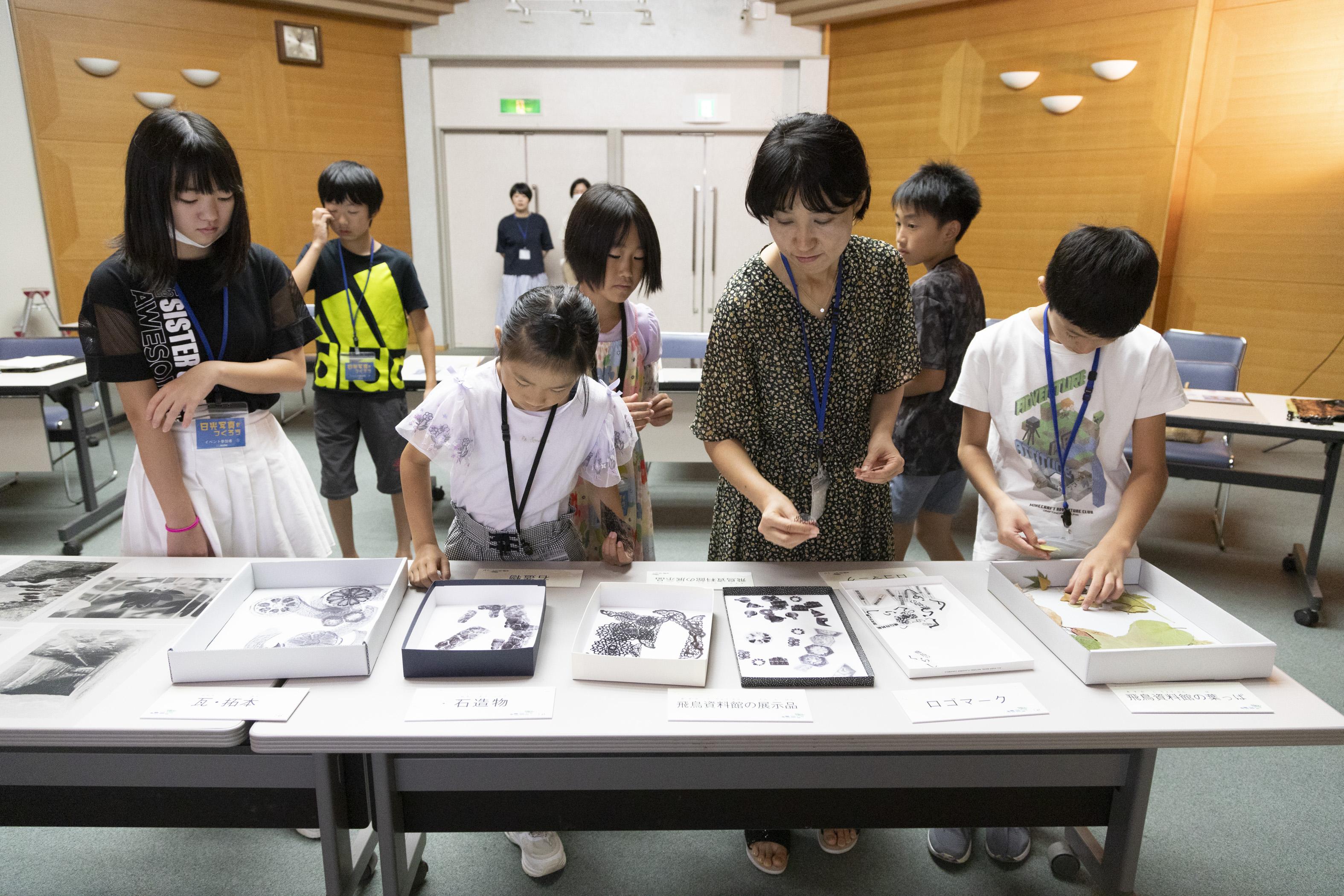 机の上に並べられたモチーフを選んでいる参加者7人の画像