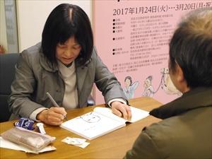 サインをする早川和子さんの写真