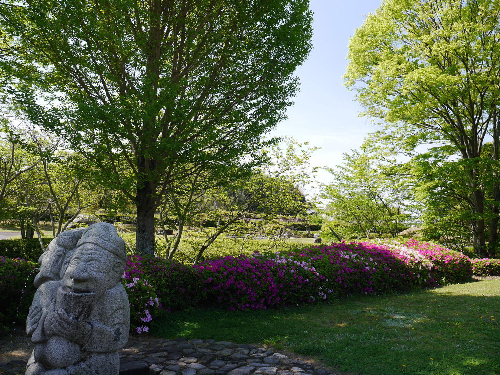 庭園の石人像とツツジの写真