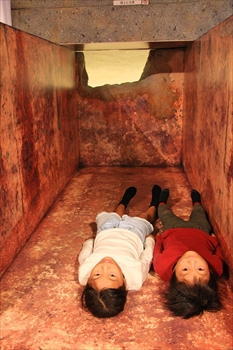 石室模型の中で寝そべる子供たちの写真